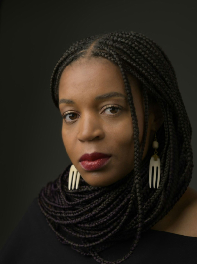 Black woman with gold earrings on black background
