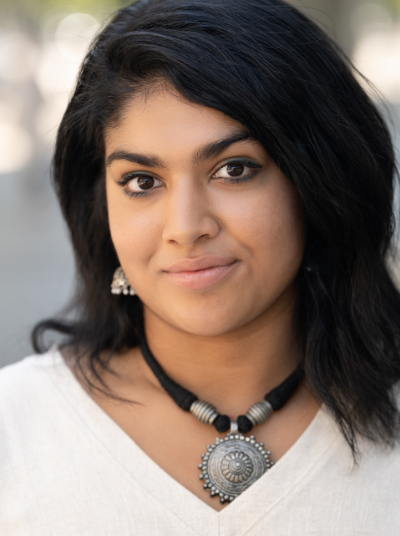 Woman with black hair, dark eyes, white shirt and black and silver necklace