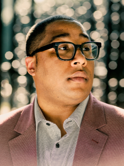 Black man with glasses and brown suit jacket