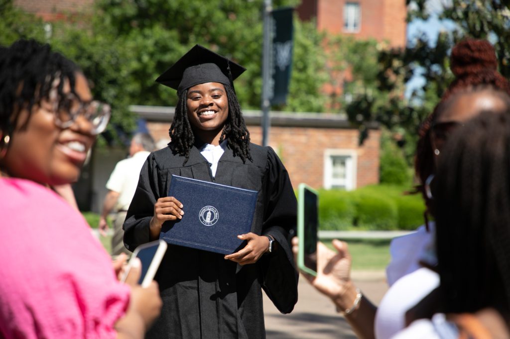 woman holds diploma outside after graduation