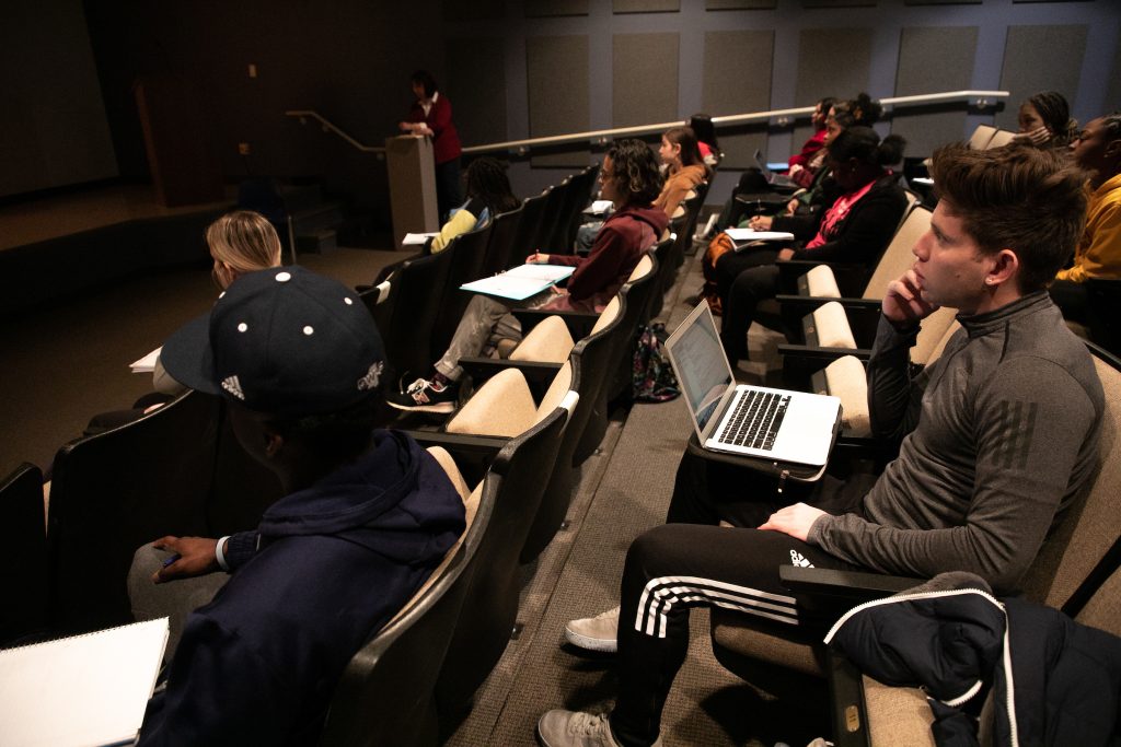 Students in a theater-style classroom with their laptops out