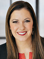Headshot of Amy Bogue smiling and wearing a black blazer and bright red lipstick to match her blouse.