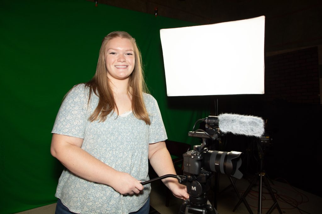 Emma Brown stands posed with camera equipment utilized by students in the Documentary Studies Concentration.