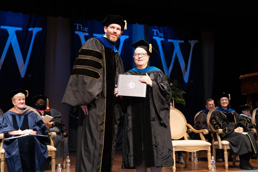 Dr. Scott Tollison and Dr. Bonnie Oppenheimer stand on stage during commencement.