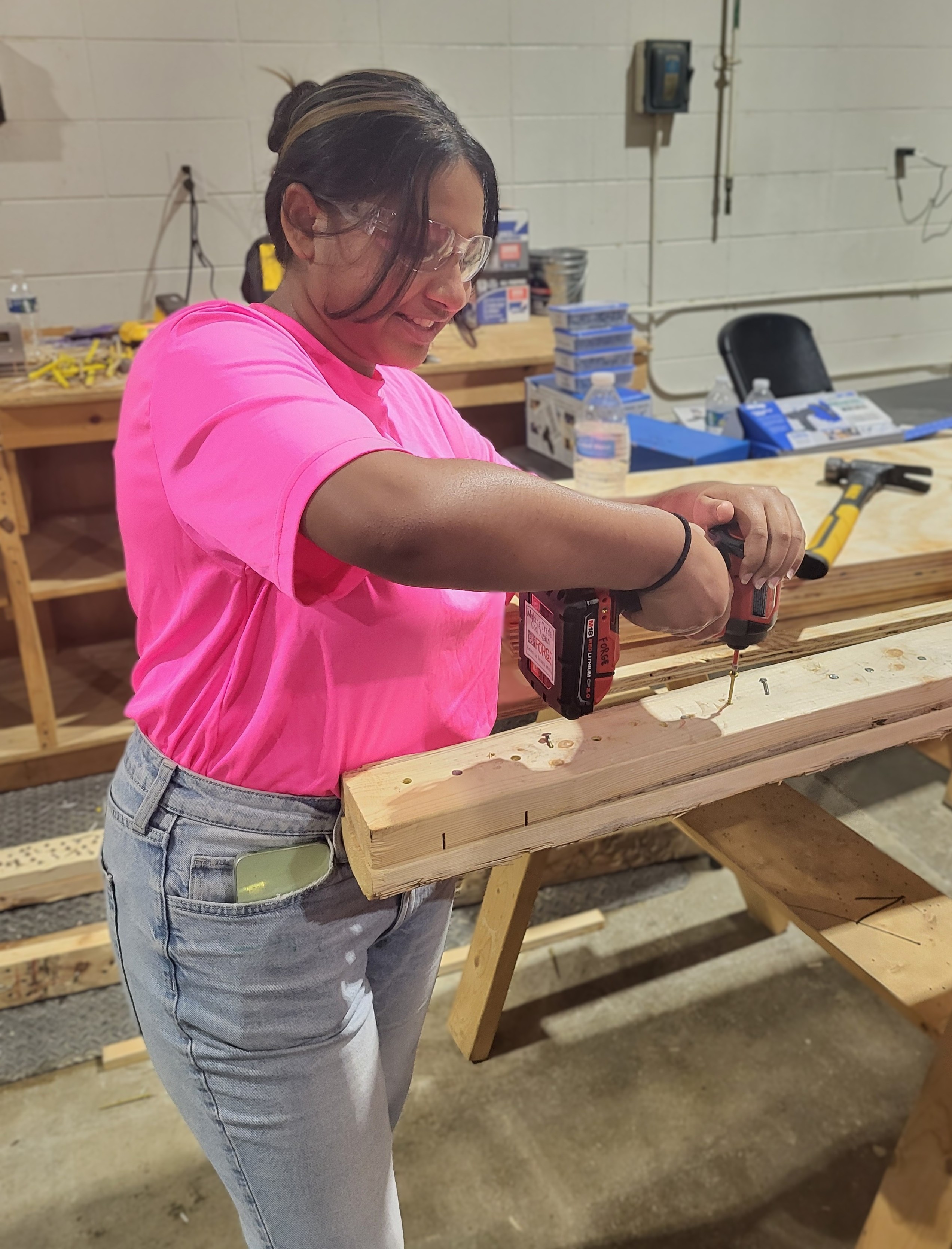 A Nancy Yates Fellow uses an impact driver while constructing a food pantry box