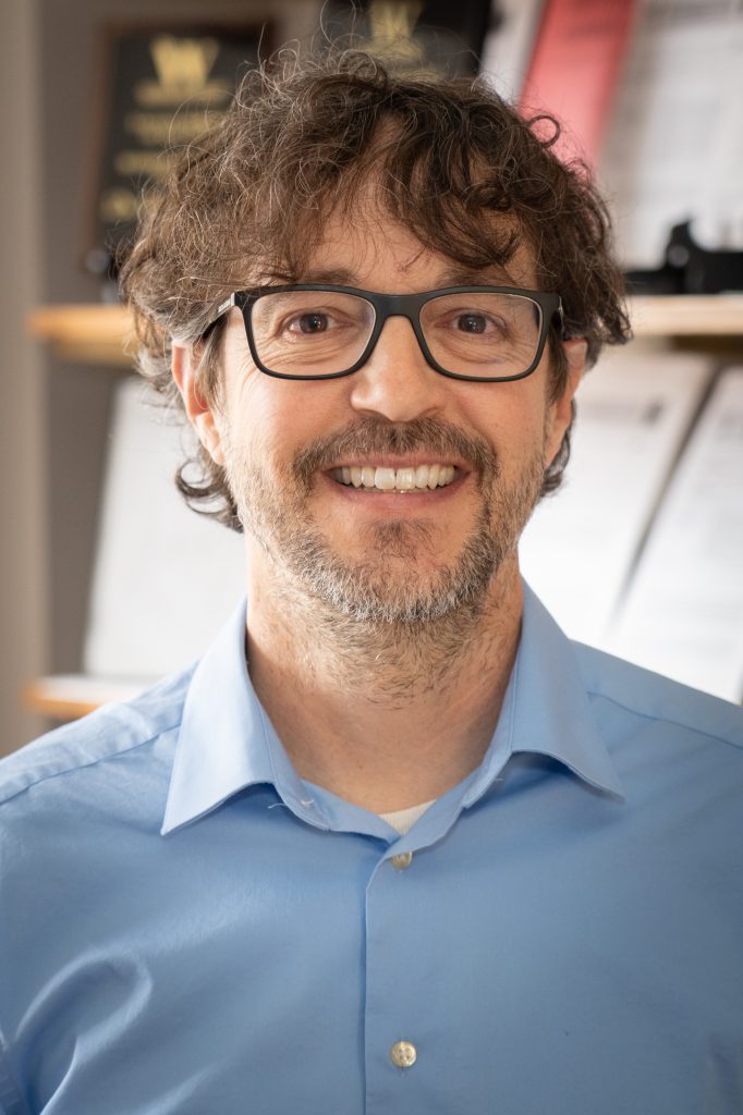 Dr. Andrew Luccasen headshot taken in a classroom.