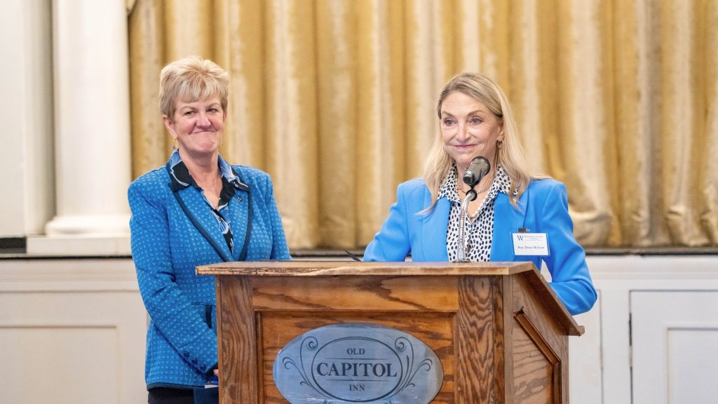 District 39 Rep. Dana McLean stands at a podium with President Nora Miller by her side
