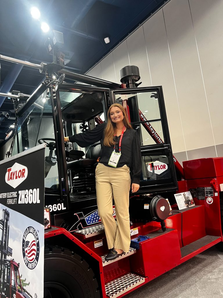 Matlyn Lowrey stands on the steps of a forklift