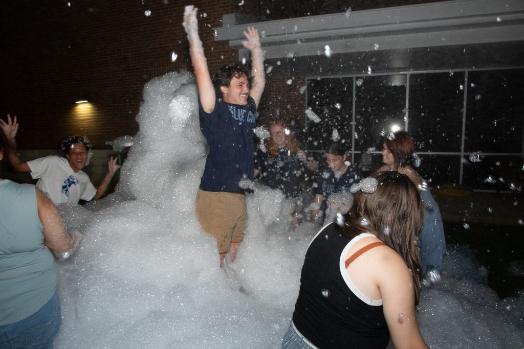 A student leaps into a pile of foam during the foam party for Blues Week 2025