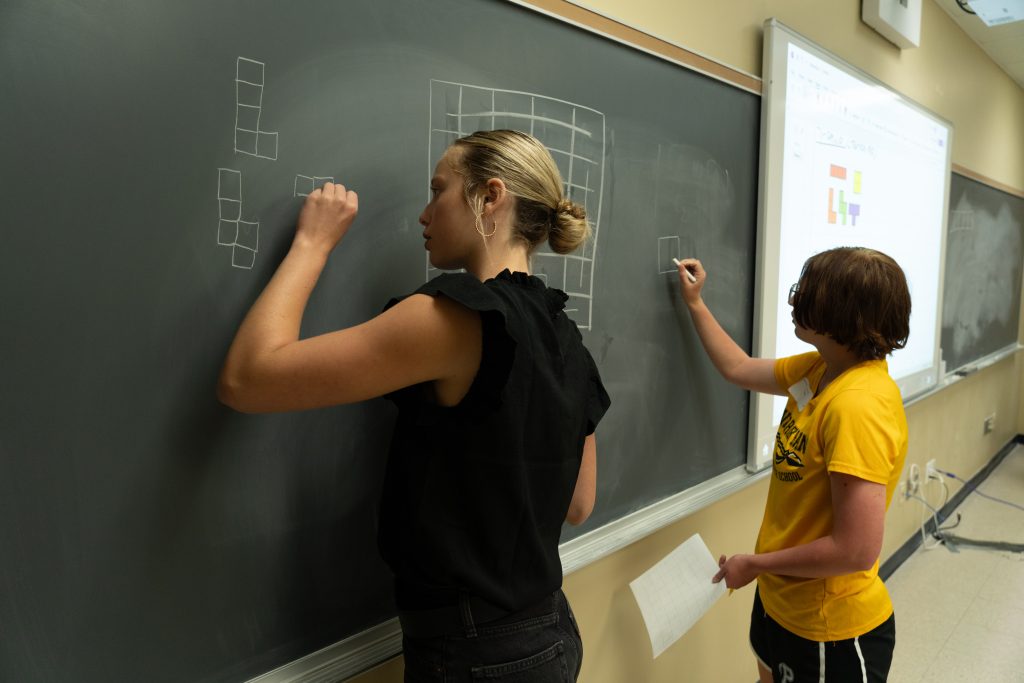 Students draw on a chalk board