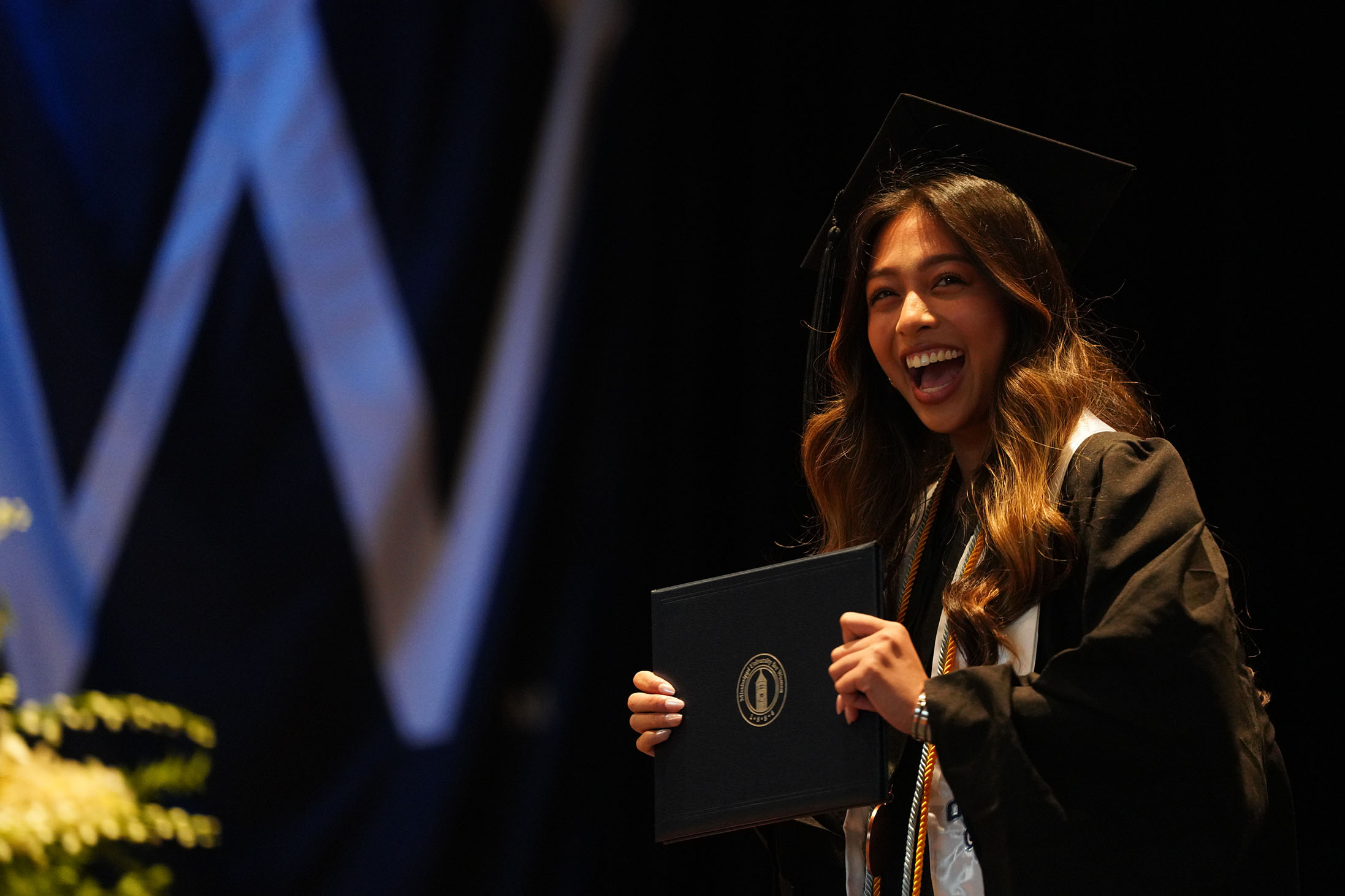 MUW Gradate excitedly showing their diploma on stage
