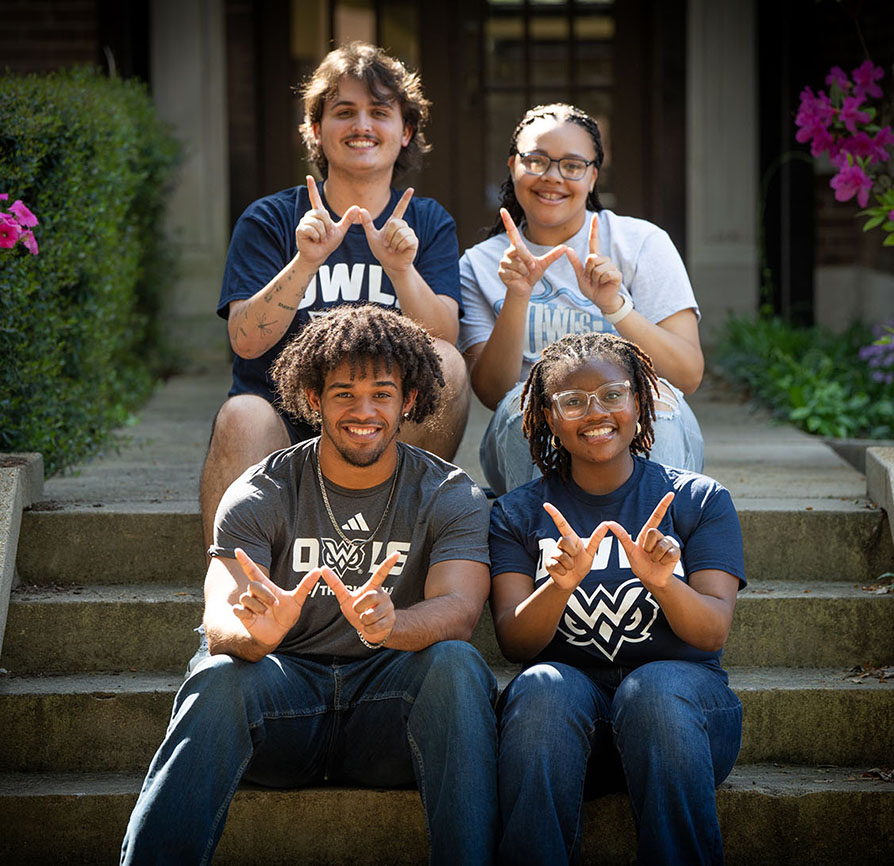 Four students making the letter W with their hands